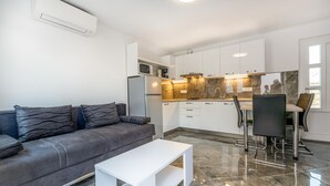Een moderne keuken met witte kastjes, een ingebouwde magnetron en een marmeren spatwand.