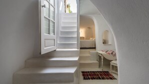 Un escalier blanc menant à une chambre à coucher où se trouvent un lit et une petite table.