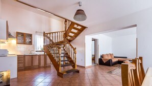 A spacious living area with a wooden staircase, a kitchen with wooden cabinets, and a dining area. - Large apartment with air conditioning, WiFi (Premantura)