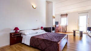 A modern bedroom with a large bed, a nightstand with a lamp, a dresser, and a television. - Large apartment with air conditioning, WiFi (Premantura)
