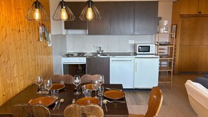 Une cuisine compacte équipée d’un four à micro-ondes, d’une cuisinière et d’un évier. On y trouve une table à manger avec des chaises et des verres à vin.