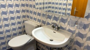Une salle de bain avec des toilettes, un lavabo et un miroir.