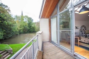 Enjoy a serene river view from this balcony with a seating area and table.