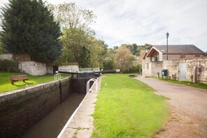 Sit on the grassy bank and enjoy the tranquil riverside view from a wooden bench.