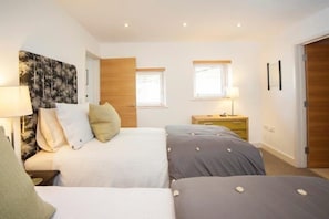 Two single beds with pillows and bedside tables, each with a lamp, are featured in this stylish bedroom.
