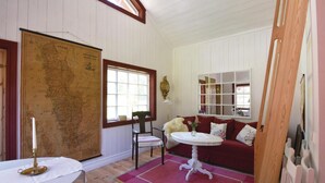 A room with a large map, a red sofa, a small table, and a window with a view.