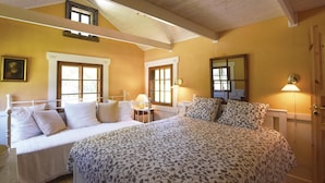 A bedroom with a large bed, two bedside tables, and two windows.