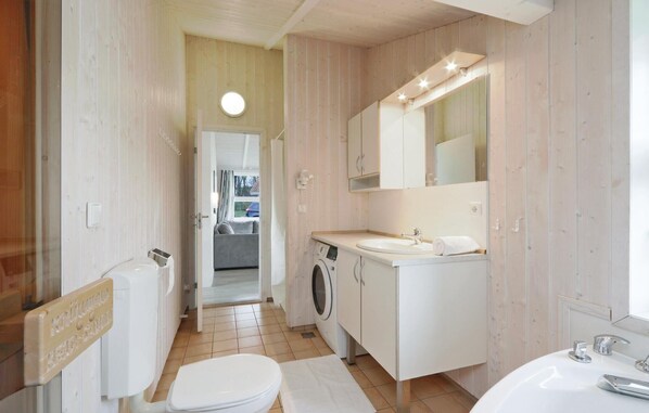 Une petite salle de bain comprenant des toilettes, un lave-linge et un lavabo.