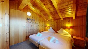 Ein Zimmer mit Holzboden, zwei Betten, einem Kleiderschrank und einem Kleiderständer.