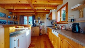 Eine Holzhüttenküche mit Kühlschrank, Herd und Kaffeemaschine.