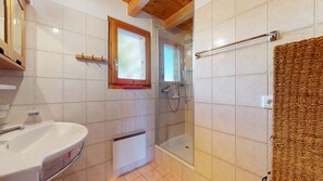 Een badkamer met een wastafel, douche en raam.