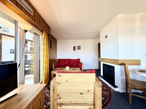 Un salón moderno con una mesa de centro de madera, un sofá rojo, un televisor y una chimenea.