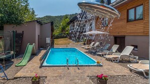 A swimming pool with a water feature, surrounded by lounge chairs and a slide. - Beautiful home in Plaski (Plaski)
