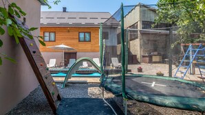 A backyard with a trampoline, a climbing wall, and a pool area. - Beautiful home in Plaski (Plaski)