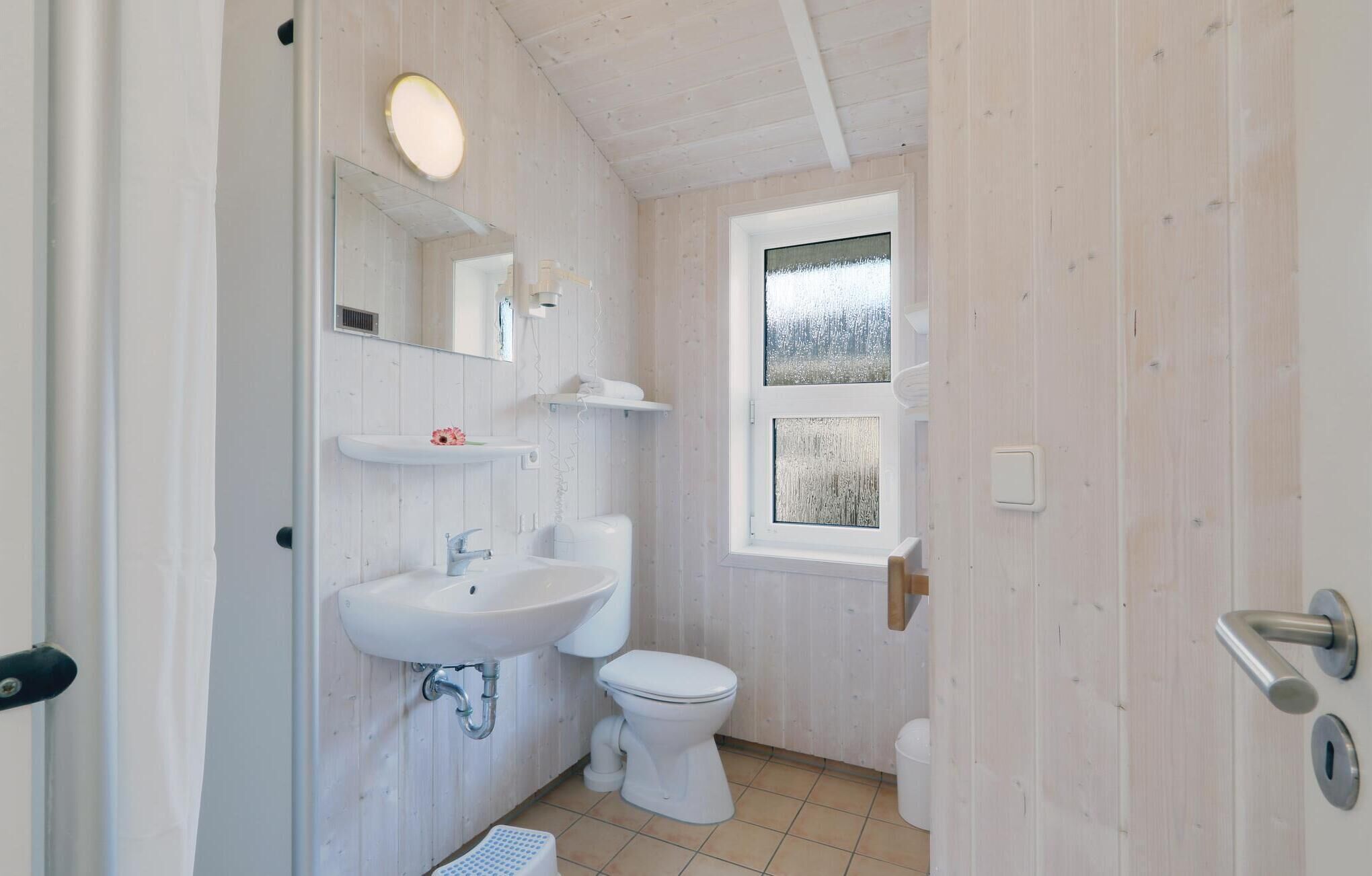 A small, white-walled bathroom with a toilet, sink, and mirror.