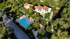 Vue aérienne d’une propriété dotée d’une piscine, de plusieurs bâtiments et d’une végétation luxuriante.