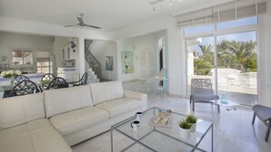 A spacious living area with a sofa, coffee table, and chairs, a staircase, and a view of the outdoors.