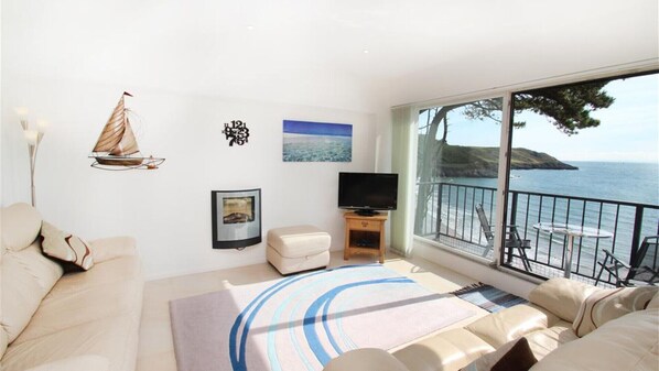 Enjoy a scenic sea view from the large window, relax in the comfortable seating area with sofa and armchairs, and unwind with a flat-screen TV.