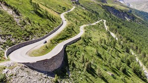 Una carretera de montaña sinuosa con un puente de piedra.