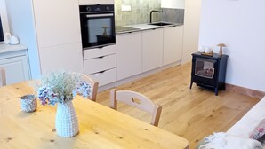 Una cocina moderna con armarios blancos, una mesa de comedor de madera y una sala de estar acogedora con sofá y una mesita auxiliar.