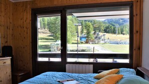 A bedroom with a bed, a window, and a view of a train track and greenery. - 2-Room Apartment, Sleeps 6, Ski-in/Ski-out, South Facing, Pets Allowed (Risoul)