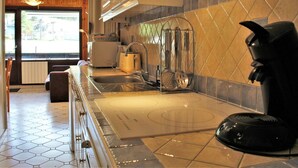 A modern kitchen with a built-in stove, a coffee maker, and a hanging utensil rack. - 2-Room Apartment, Sleeps 6, Ski-in/Ski-out, South Facing, Pets Allowed (Risoul)