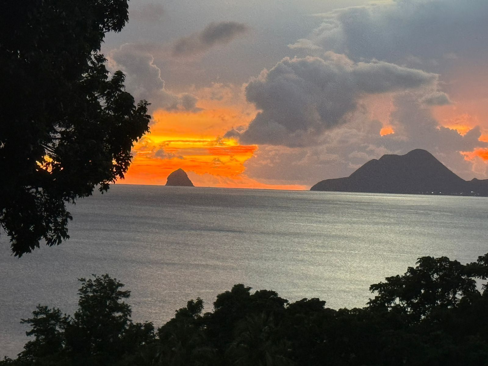 A sunset over a calm sea with distant landforms.