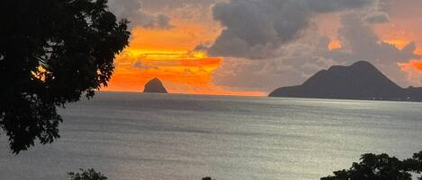 A sunset over a calm sea with distant landforms.