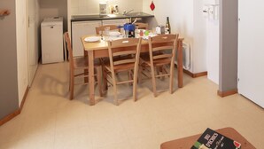Een compacte keuken met een eethoek, een magnetron, een koffiezetapparaat en een kleine koelkast.