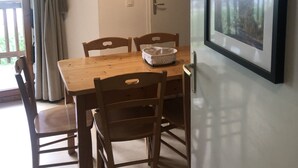 A dining area with a wooden table and chairs, a clock on the wall, and a framed picture on the wall.