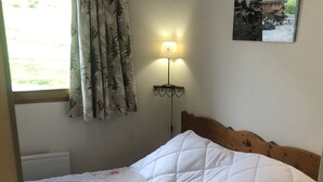 A bed with a quilted white duvet, a wooden headboard, and a bedside lamp with a heart-shaped light fixture.