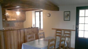 A dining area with a checkered tablecloth, wooden chairs, a clock on the wall, and a door with windows. - Cottage in the countryside, in the Tarn, between Aveyron and Hérault (Berlats)
