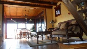 Amplia sala de estar con techo de madera, un sofá, una mesa y una silla.