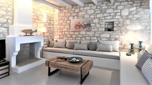 Un salon chaleureux avec un mur en pierre, une cheminée, un canapé et une table basse.