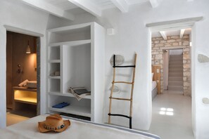 Una habitación con cama, armario, escalera y baño con pared de piedra.