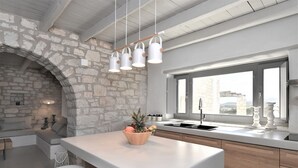 Une cuisine moderne avec un mur en pierre, une grande fenêtre et un îlot central doté de tabourets.