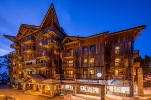 A multi-story wooden building with balconies, a ski hire sign, and a chalet de bois.