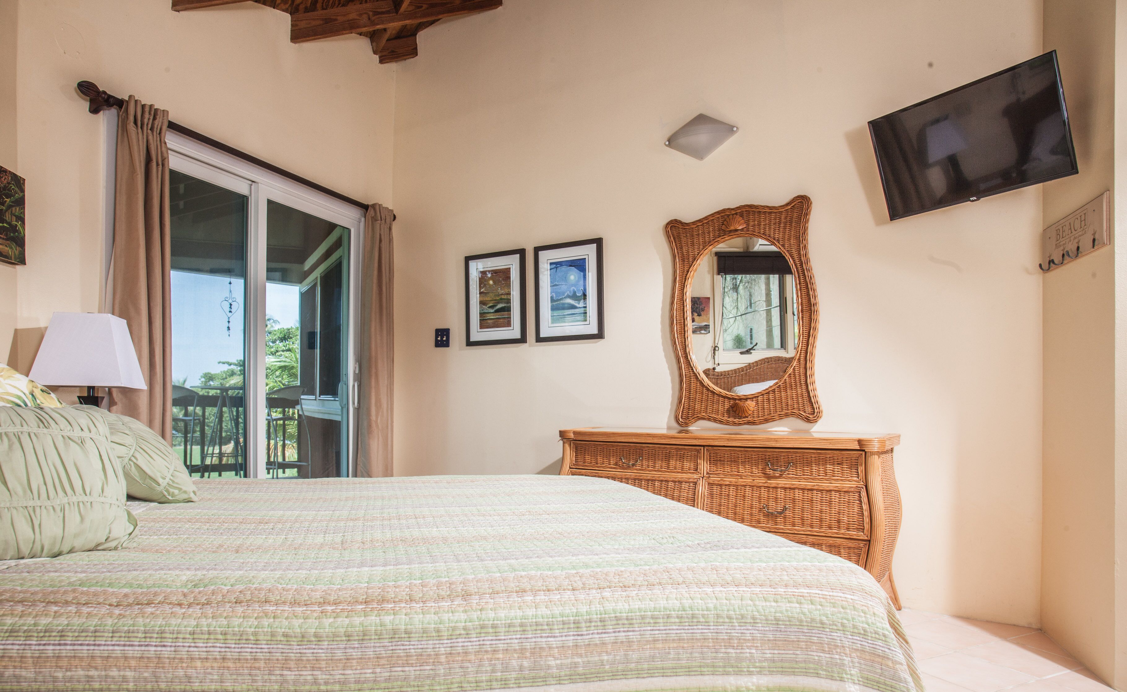 A bedroom with a bed, a dresser, a television, and a window with curtains.
