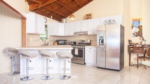 A modern kitchen with white cabinets, stainless steel appliances, and a bar area with stools.