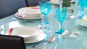 A dining table with blue glassware, plates, and a vase with yellow flowers. - Protaras Villa Michelle 8 Near The Beach (Protaras)