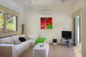 A modern living room with a sofa, a coffee table, a TV on a stand, and a painting on the wall.