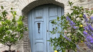 A rustic stone building with a blue door, potted plants, and lavender flowers. - Natural stone country house (Arcevia)