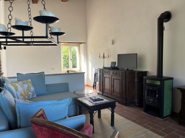 A living room with a sofa, a table, a television, a cabinet, and a fireplace.