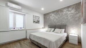 A bedroom with a large bed, a window with blinds, a radiator, and a grey textured wall. - Spacious 5 bedroom Stone Villa with Private Pool and Sea view  (Mlini)