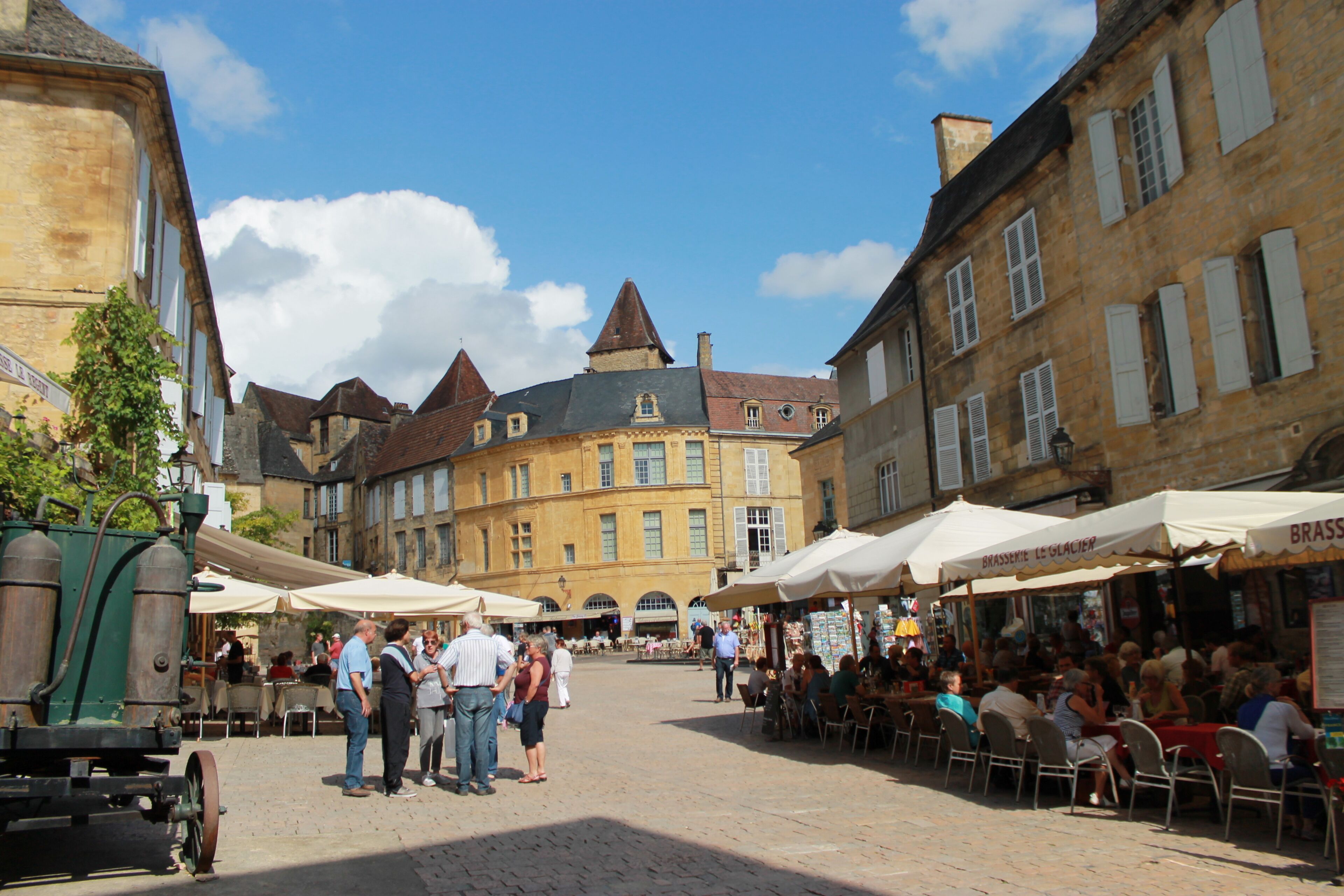 A historic European street with cobblestone pavement, traditional buildings, and outdoor cafes.