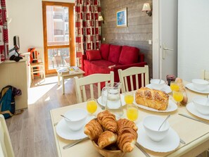 A breakfast setup with croissants, orange juice, and a bread roll on a table with white plates and cups. - Apartment in Valmeinier with Valley Views (Valmeinier)