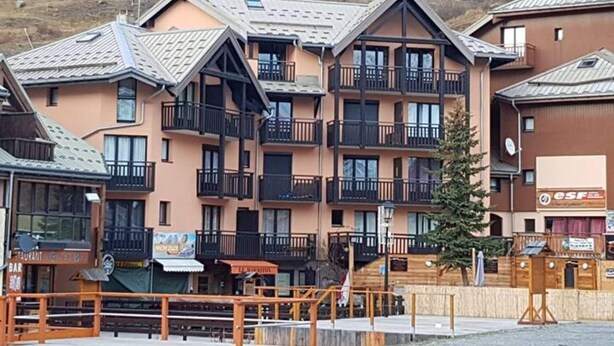 Et hotel med flere etager, altaner, et skiløbsresorts skilt og et træhegn.