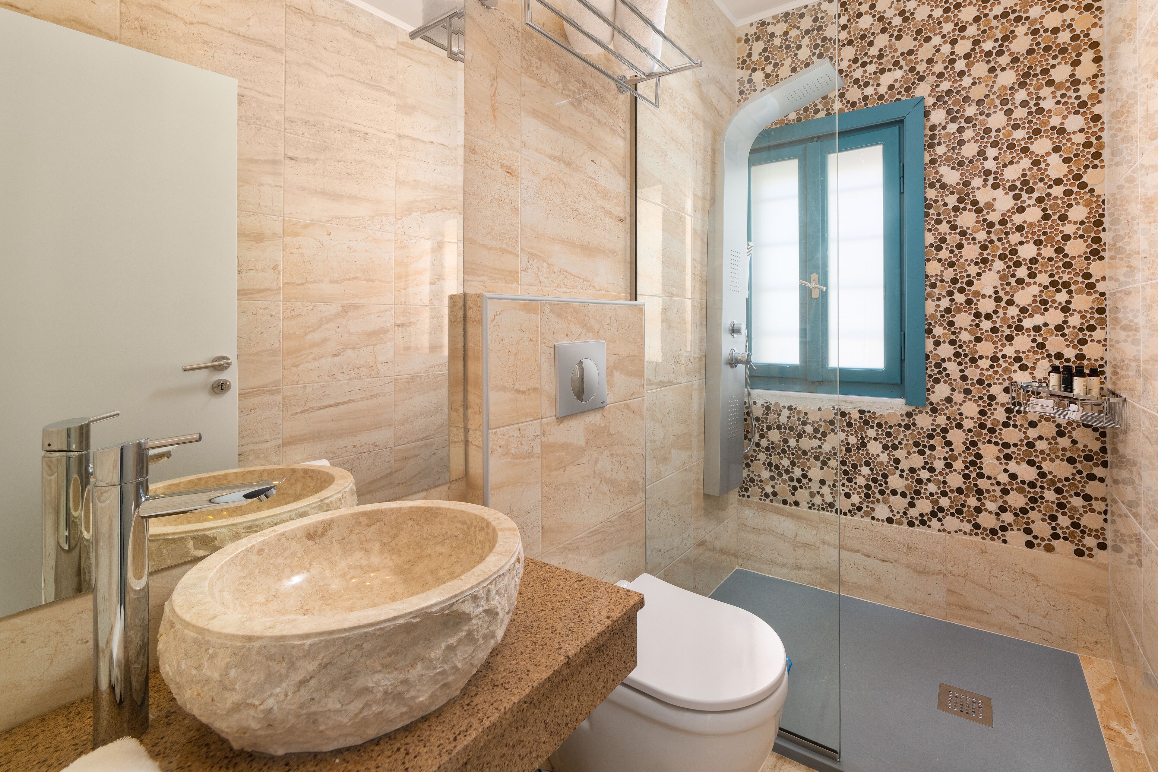 Ein modernes Badezimmer mit einem großzügigen Steinsink, einer weißen Toilette und einer Duschkabine.