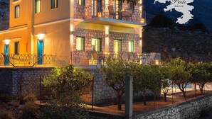 A two-story building with stone facade, balconies, and outdoor seating. - Royal Villa Pedi - Symi (Symi)