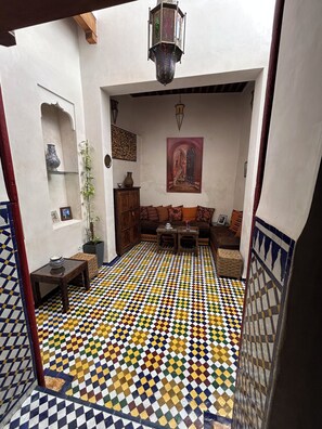 A living room with a patterned floor, a sofa set, a wooden cabinet, and a hanging lantern. - DAR SEFFAH :Your house in the heart of the Fes' Medina (fes)